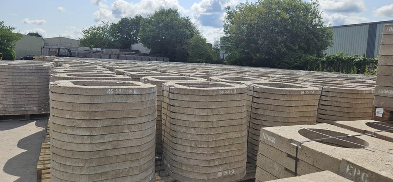 Stacks of precast concrete seating rings and cover slabs in a storage yard