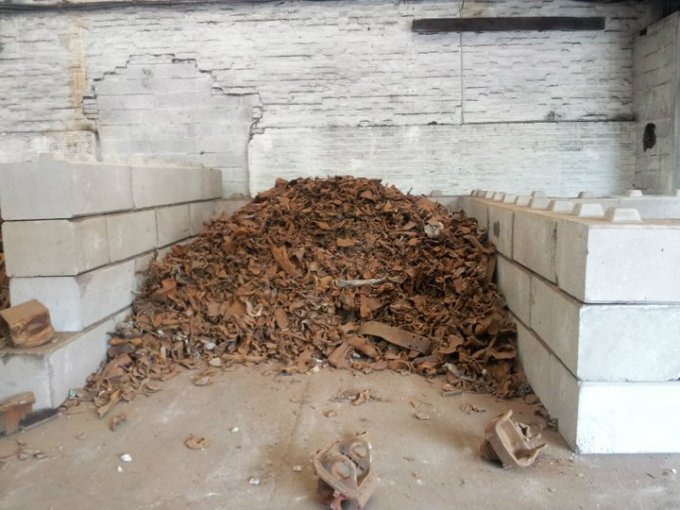 Rusted scrap heaped in a bay formed by stacked Duo blocks
