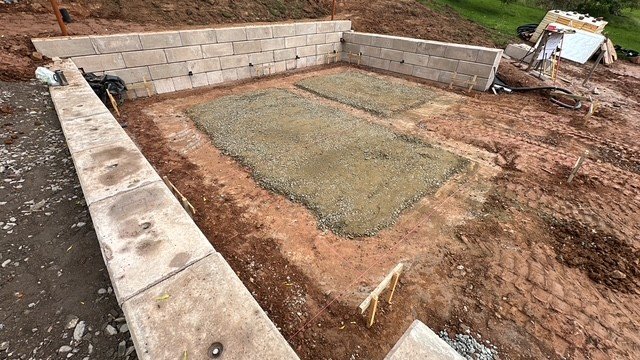 Interlocking block walls enclosing a freshly poured concrete slab base