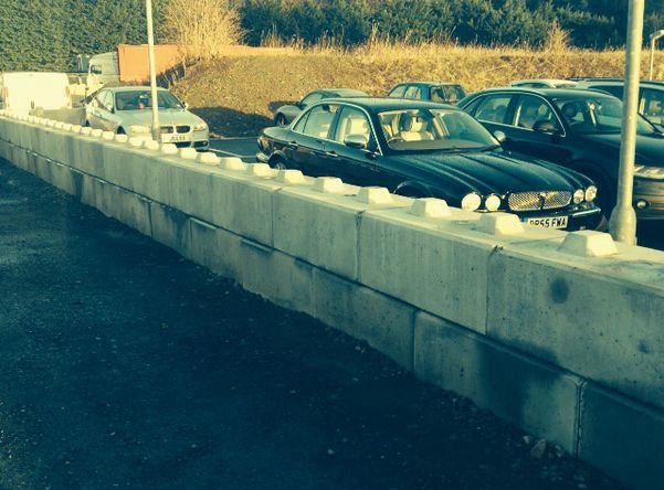 Duo block barrier wall separating parked cars from open ground