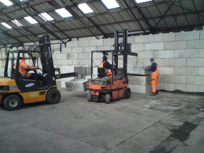 Two forklifts building a Duo block dividing wall inside a warehouse