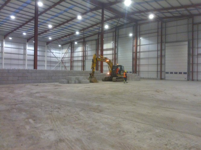 Low Duo block dividing wall across a warehouse floor with an excavator beyond