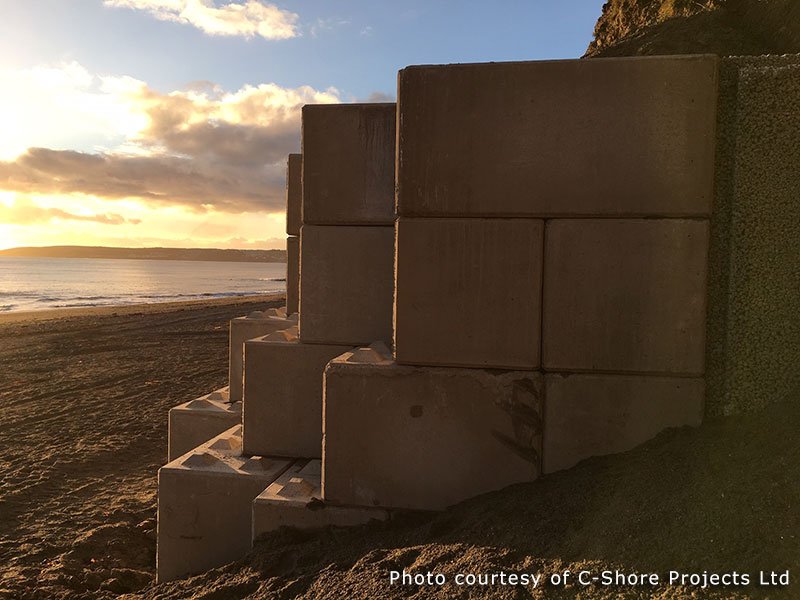 Stepped end of a Legato block sea wall on the beach at sunset