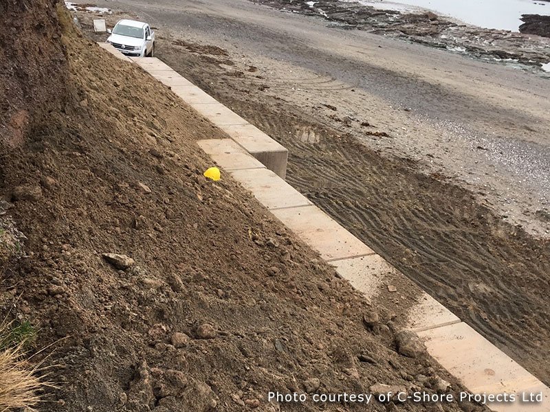 Concrete block wall retaining an earth bank along a coastal road