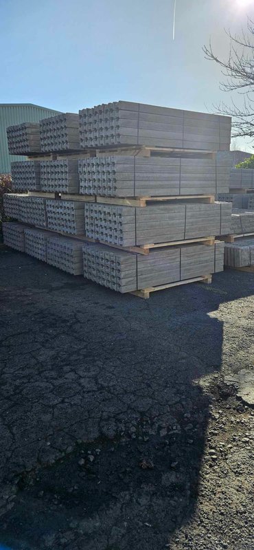 Stacked pallets of concrete fence posts in a storage yard