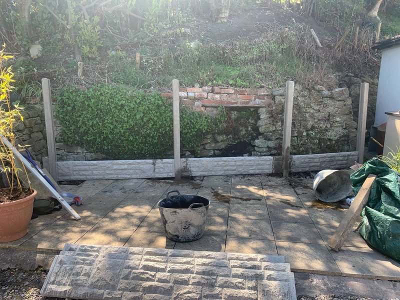 Concrete fence posts and gravel boards being installed to retain a garden bank