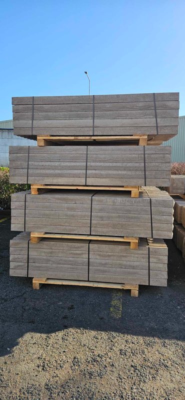 Banded pallets of precast concrete fence posts stacked in a yard
