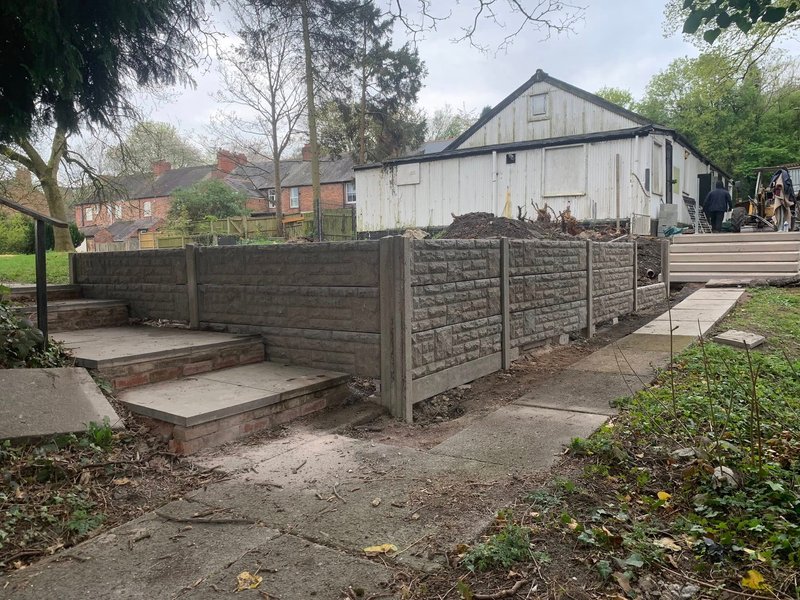 Rock-faced concrete gravel boards retaining a bank beside a garden path