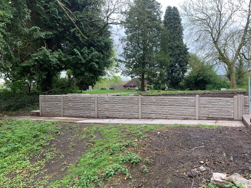 Concrete post and gravel board fence enclosing a grassed garden