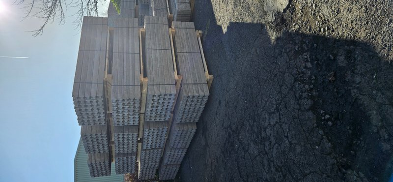 Bundles of semi-dry precast concrete fence posts stacked in a yard