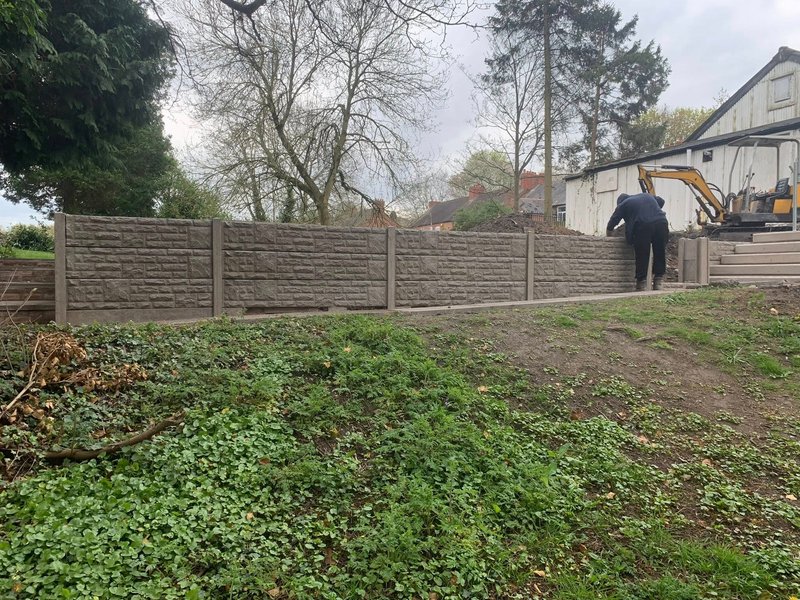 Run of rock-faced concrete gravel boards and posts installed along a bank