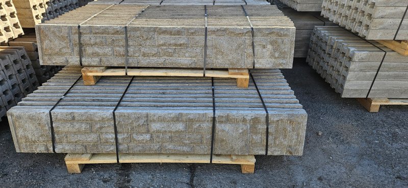 Pallets of rock-faced decorative concrete gravel boards stacked outdoors
