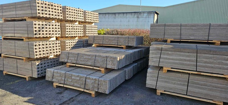 Decorative gravel boards and slotted concrete fence posts stacked on pallets