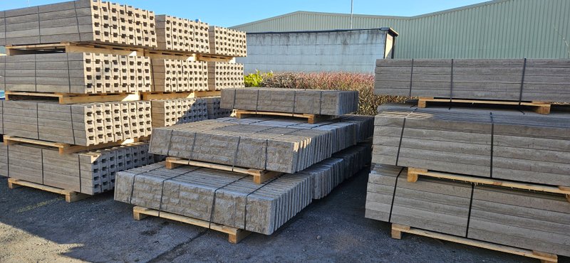 Pallets of concrete fence posts and gravel boards stacked in a storage yard