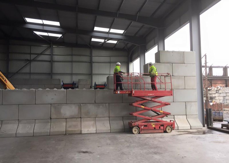 Workers on a scissor lift building a Legato block storage bay wall indoors