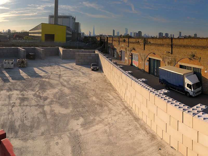 Legato interlocking block walling enclosing a waste storage yard with a city skyline beyond