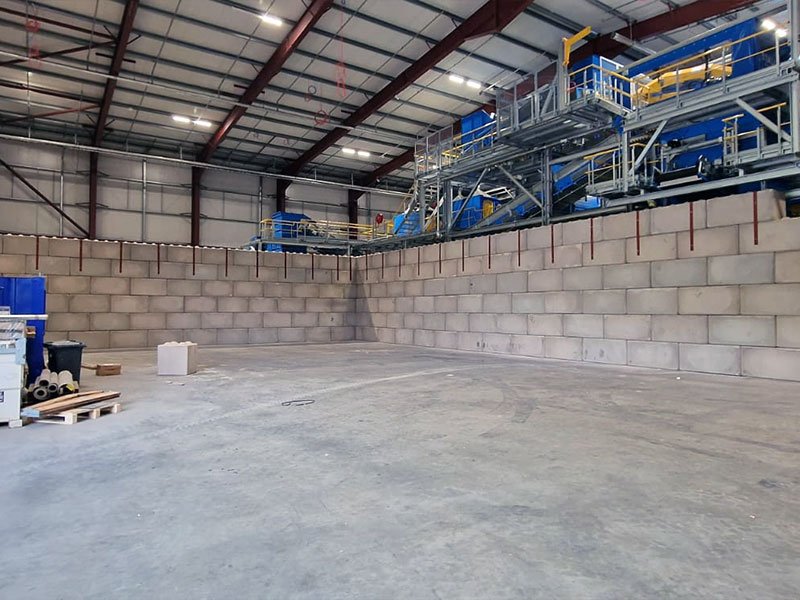 Legato block wall turning a corner beneath a processing plant inside a shed