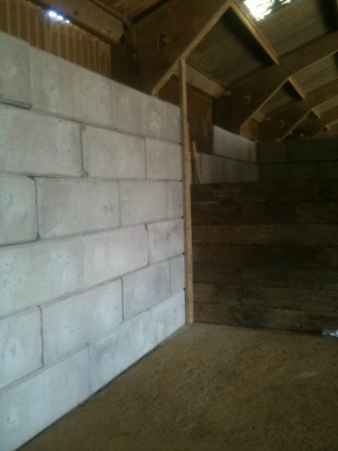 Duo interlocking block walls lining the inside of a timber-framed barn