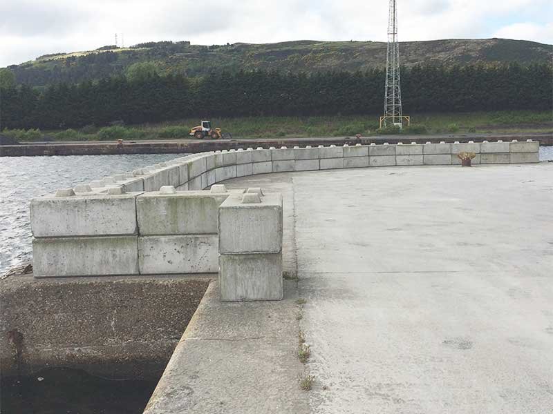 Duo blocks lining a concrete quay edge as edge protection beside water