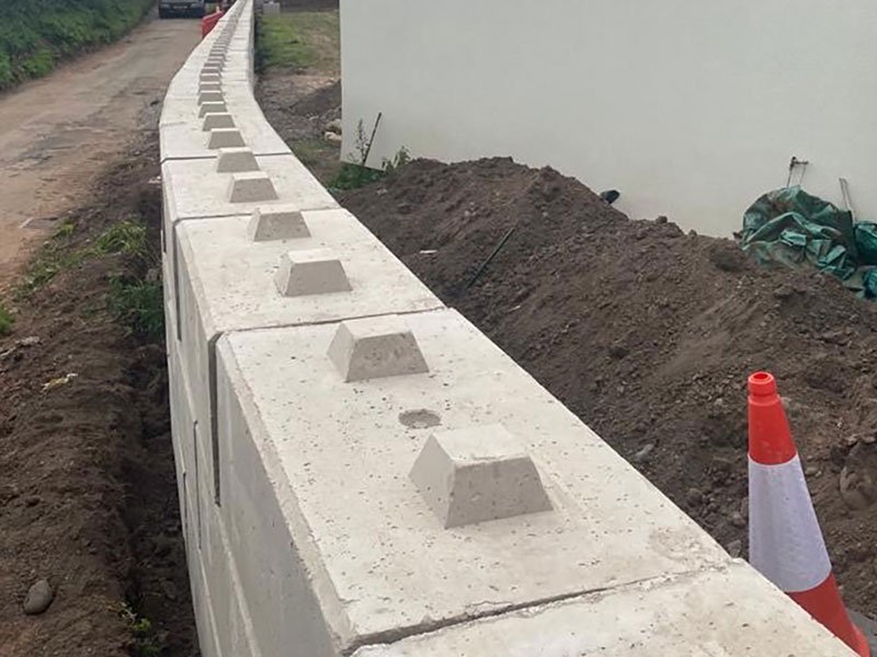 Duo interlocking blocks laid as a low flood defence wall beside a track