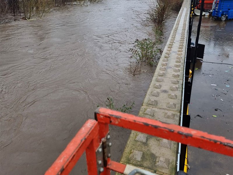 Interlocking block flood wall holding back a river in full flood