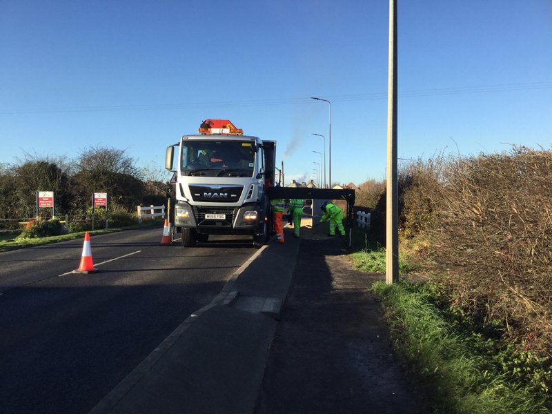 Crane-equipped lorry delivering blocks on a coned rural road