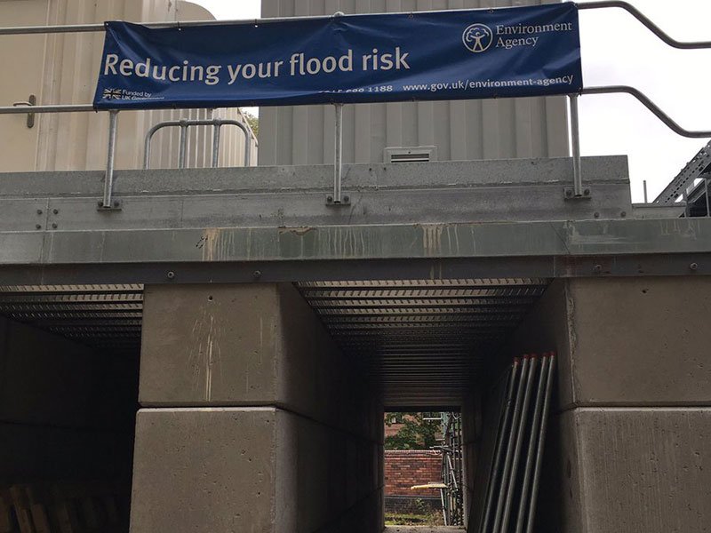 Concrete blocks supporting a temporary platform beneath a flood risk banner