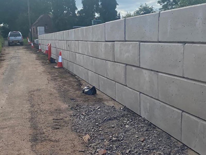 Interlocking block wall built alongside a gravel lane as a flood barrier