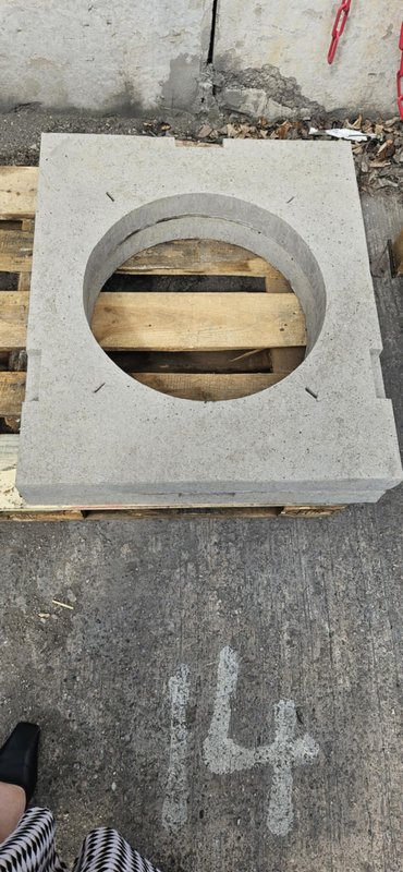 Square gully cover slab with a circular opening resting on a timber pallet