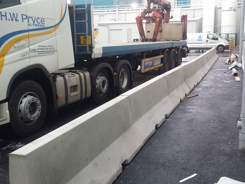 Concrete safety barrier line separating an HGV loading yard from the factory