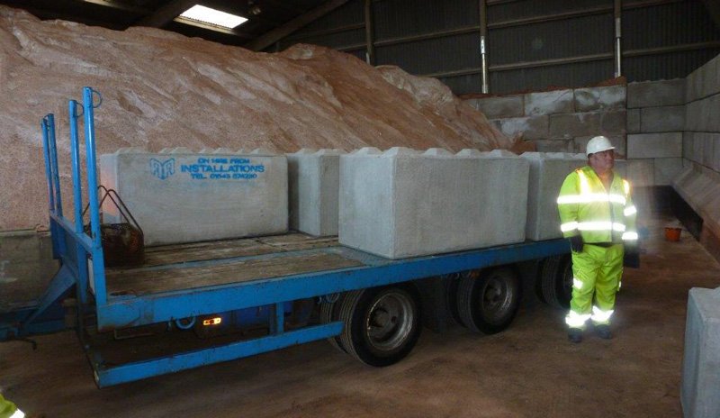Worker beside a trailer of Legato blocks in front of a salt stockpile