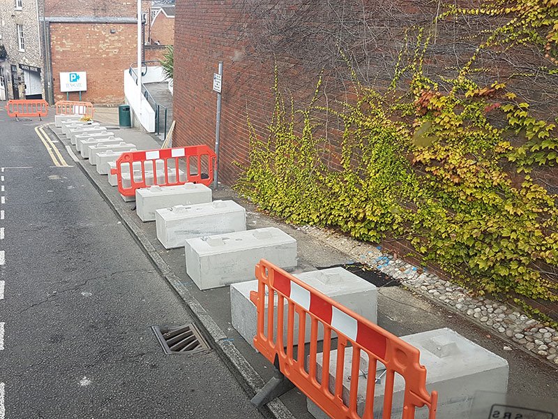Duo blocks and orange pedestrian barriers closing off a narrow city street