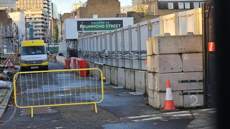 Concrete hoarding blocks supporting site fencing along a city street at Drummond Street