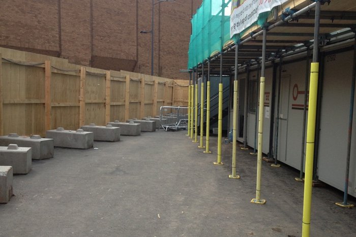 Duo blocks ballasting timber hoarding around a scaffolded construction site