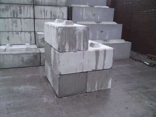 Kentledge blocks stacked in a yard in front of block walling