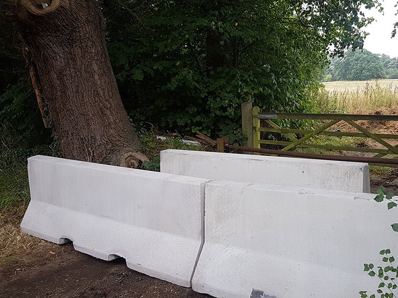Jersey barriers closing off a field gateway beside a farm track