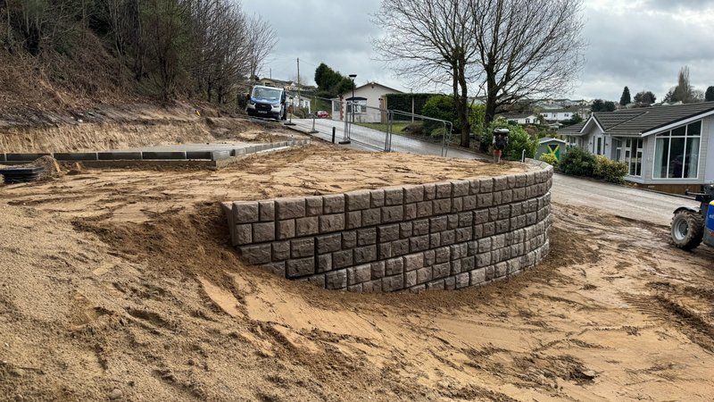 Curved cobblestone-finish Retainer-Rock wall around sandy ground at a lodge park
