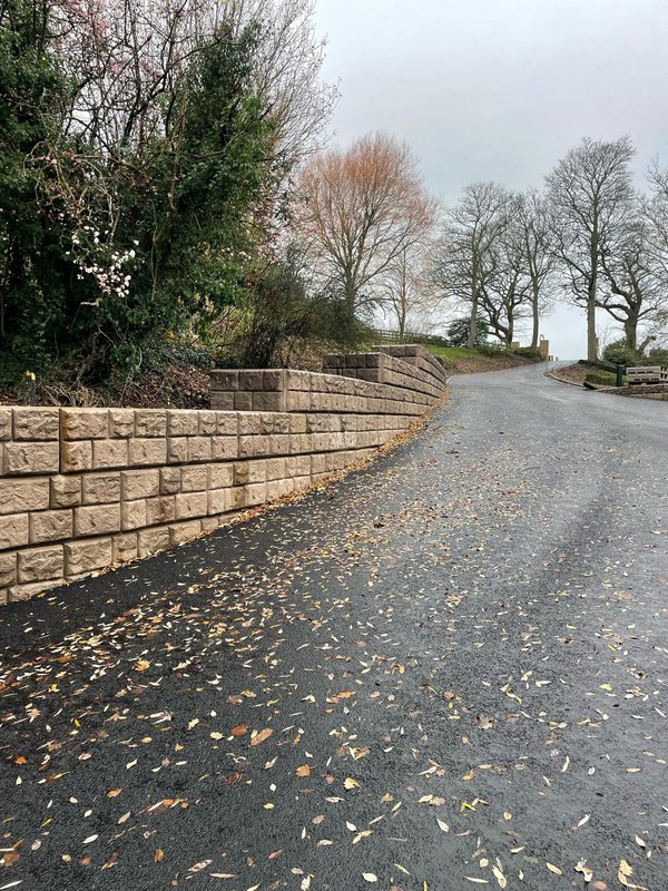 Cobblestone-finish Retainer-Rock retaining wall running along a rural lane