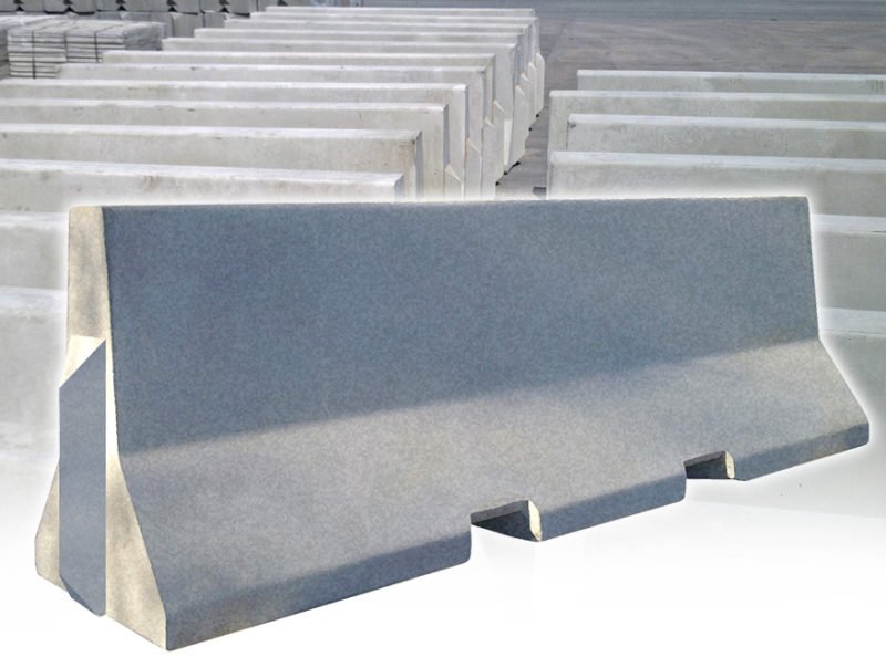 Precast Jersey barrier shown in front of a row of stacked barriers