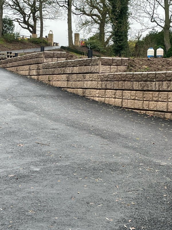 Terraced cobblestone-finish Retainer-Rock walls beside a newly surfaced driveway