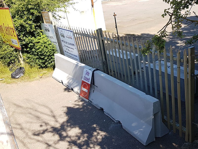 Jersey barriers set across a palisade gateway securing a yard entrance