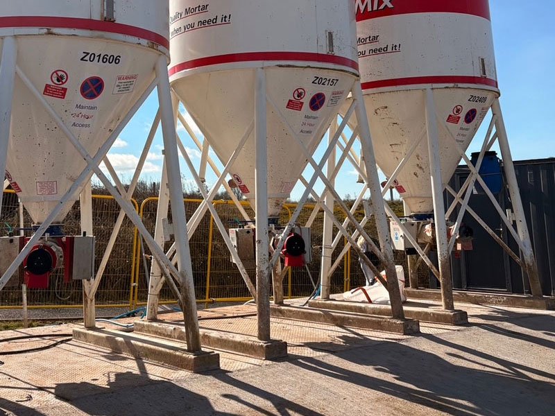 Cement silos supported on precast concrete foundation slabs in a works yard