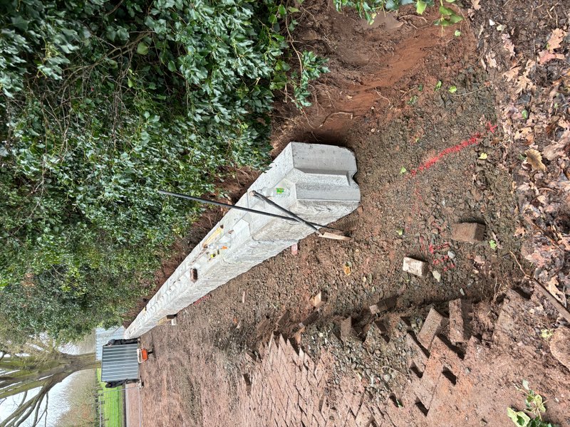 Precast walling unit being lowered into an excavated red earth bank on a slope