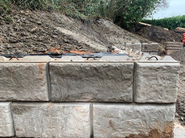 Rock-faced Vee-Rock blocks being laid to retain an excavated earth bank