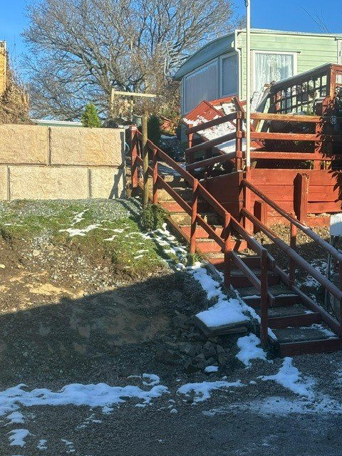 Vee-Rock walling retaining a bank below a static caravan with timber steps in snow