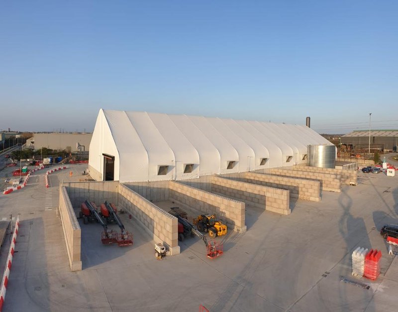 Block material bays arranged outside a large fabric covered building