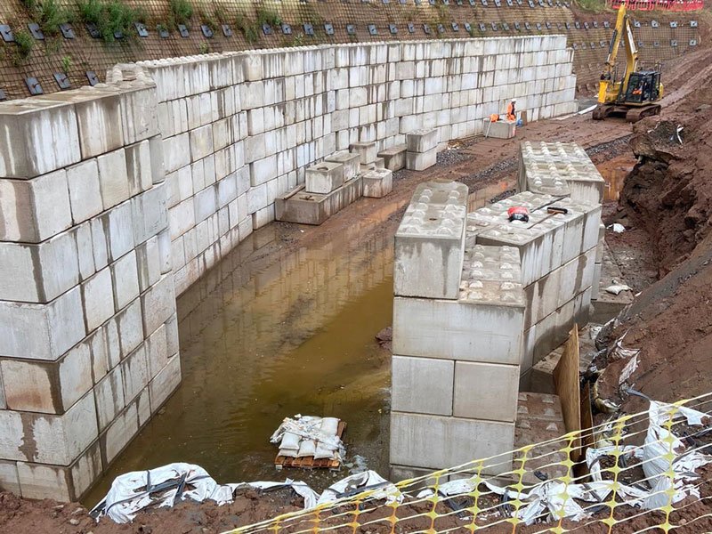 Tall interlocking block walls lining a water-filled excavation for a fish pass