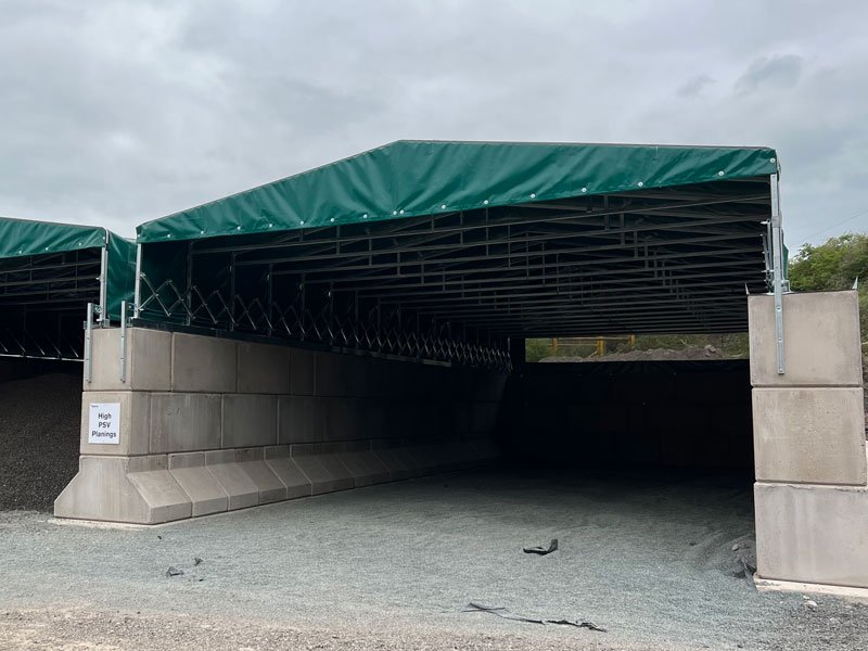 Green canopy shelter spanning storage bays walled with Legato interlocking blocks
