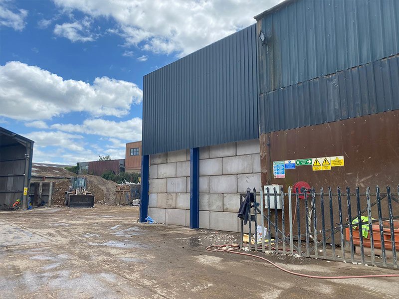 Legato block storage bay wall built against a blue-clad industrial unit