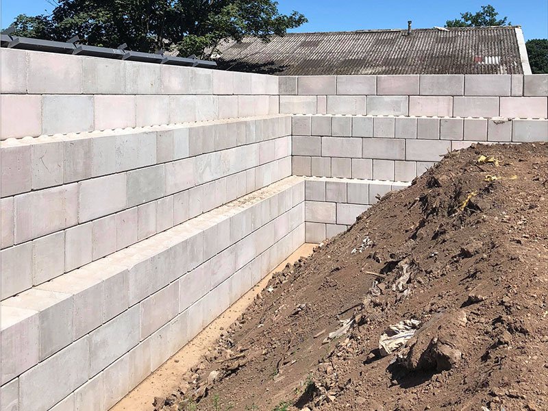 Stepped Legato interlocking block retaining wall holding back excavated ground